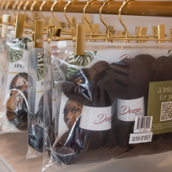 Packaged hair extensions on gold hangers with visible branding.