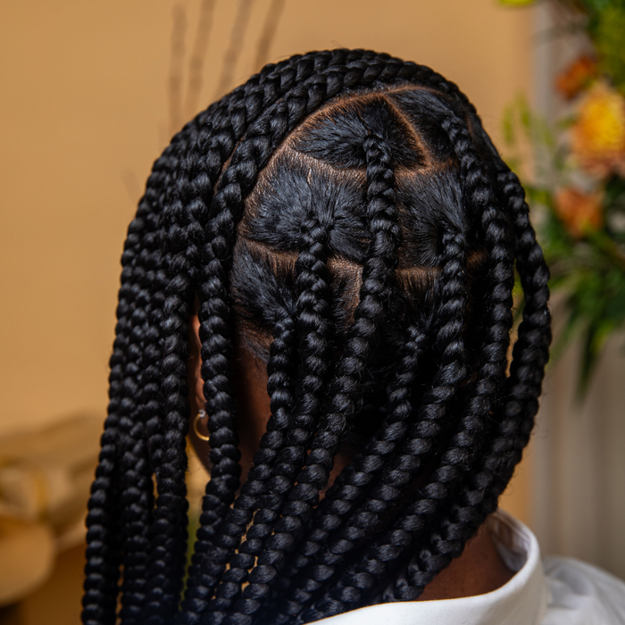 Person with braided hair in a blurred indoor setting