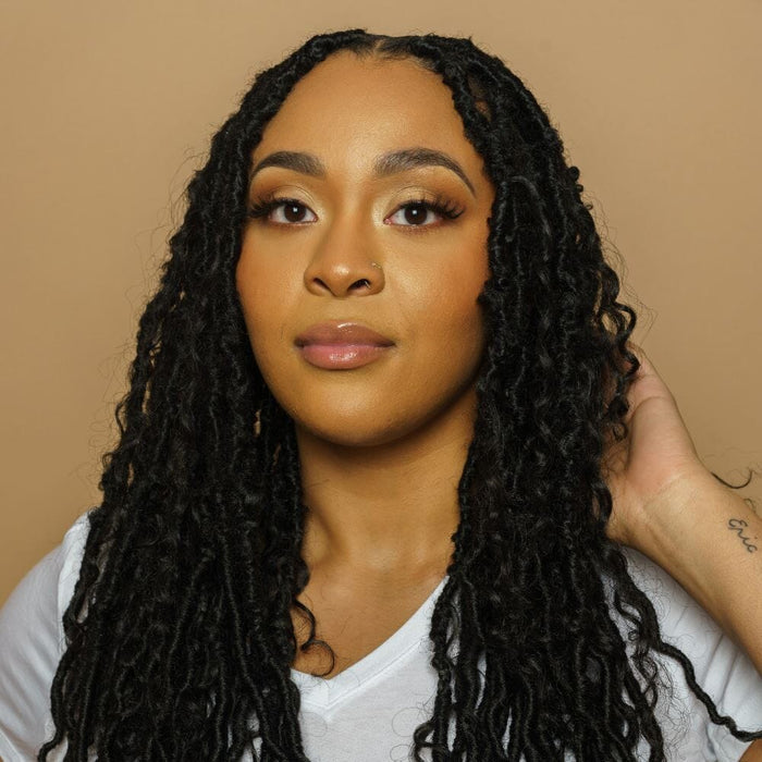 Woman smiling with crochet bantu knot style and loose curls, highlighting softness and versatility of the hair.